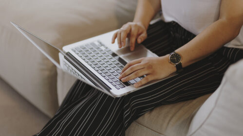 zdjęcie kobieta siedząca na kanapie i korzystająca z laptopa