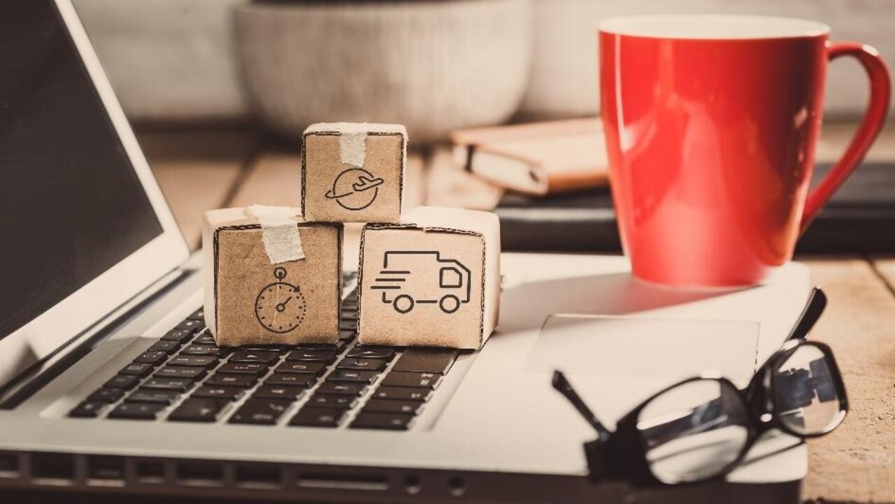 zdjęcie otwarty laptop a na nim czerwony kubek, okulary i trzy małe paczuszki z rysunkami związanymi z dostawą paczek