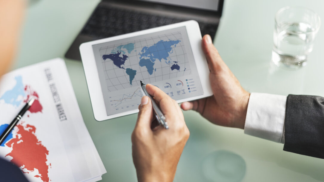 zdjęcie tablet z mapą świata na którym pracują dwie osoby
